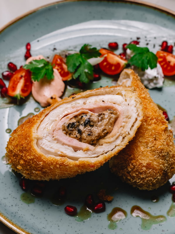 Flamenquín on a plate, accompanied by a pomegranate salad