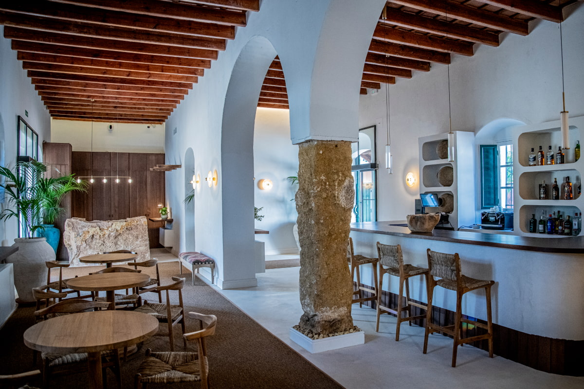 Barra de bar exquisitamente decorada junto a zona con sillas y mesas