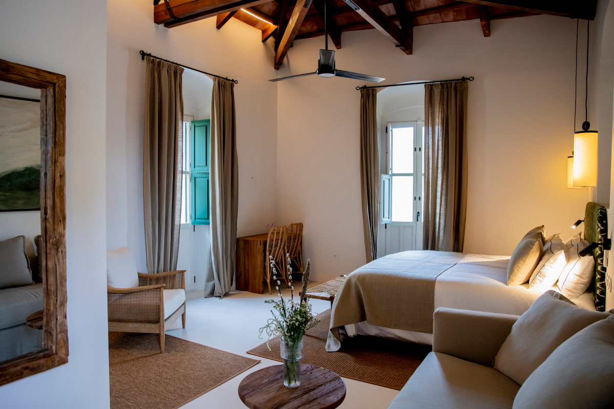 Amplia habitación decorada en tonos tierra, con espejo de cuerpo entero y ventilador de techo