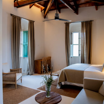 Amplia habitación decorada en tonos tierra, con espejo de cuerpo entero y ventilador de techo