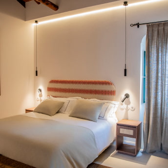 Cama en Habitacion Doble, con cabecero tapizado en colores crudo y rojizos
