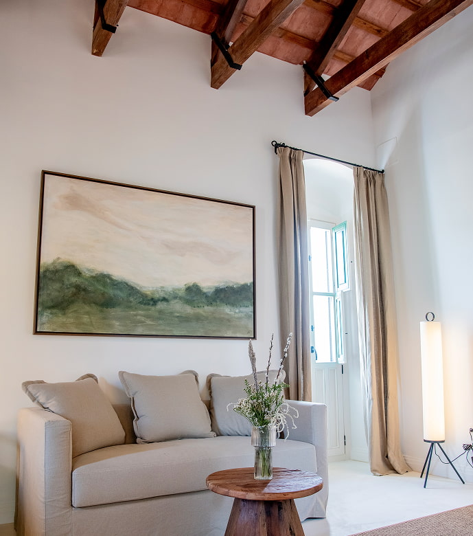 Rincón con encanto Bonito rinción del hotel en el que se ve un sofá, una mesita con decoración floral y un cuadro del paisaje