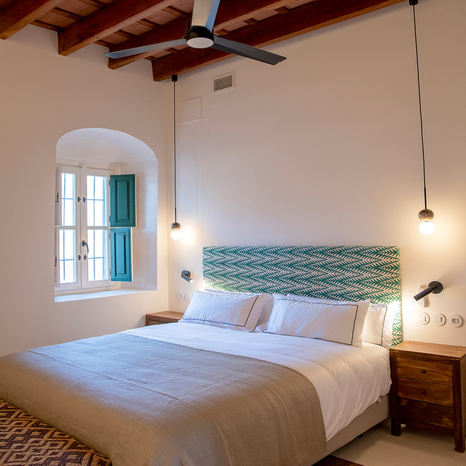 Room with double bed and decorated in green and white tones.