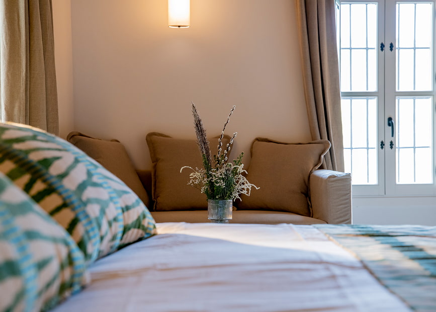Out of focus bed, with sofa and flower arrangement in background